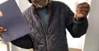 Picture shows a partial photo of a man holding keys in his left hand with a blue rental agreement folder in his right.